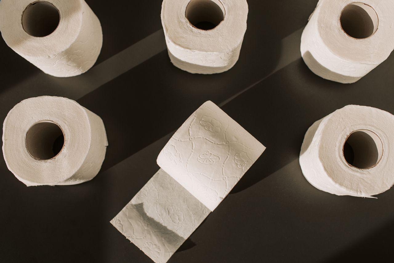 stats-img Flat lay of multiple toilet paper rolls on a dark background, artistically arranged.