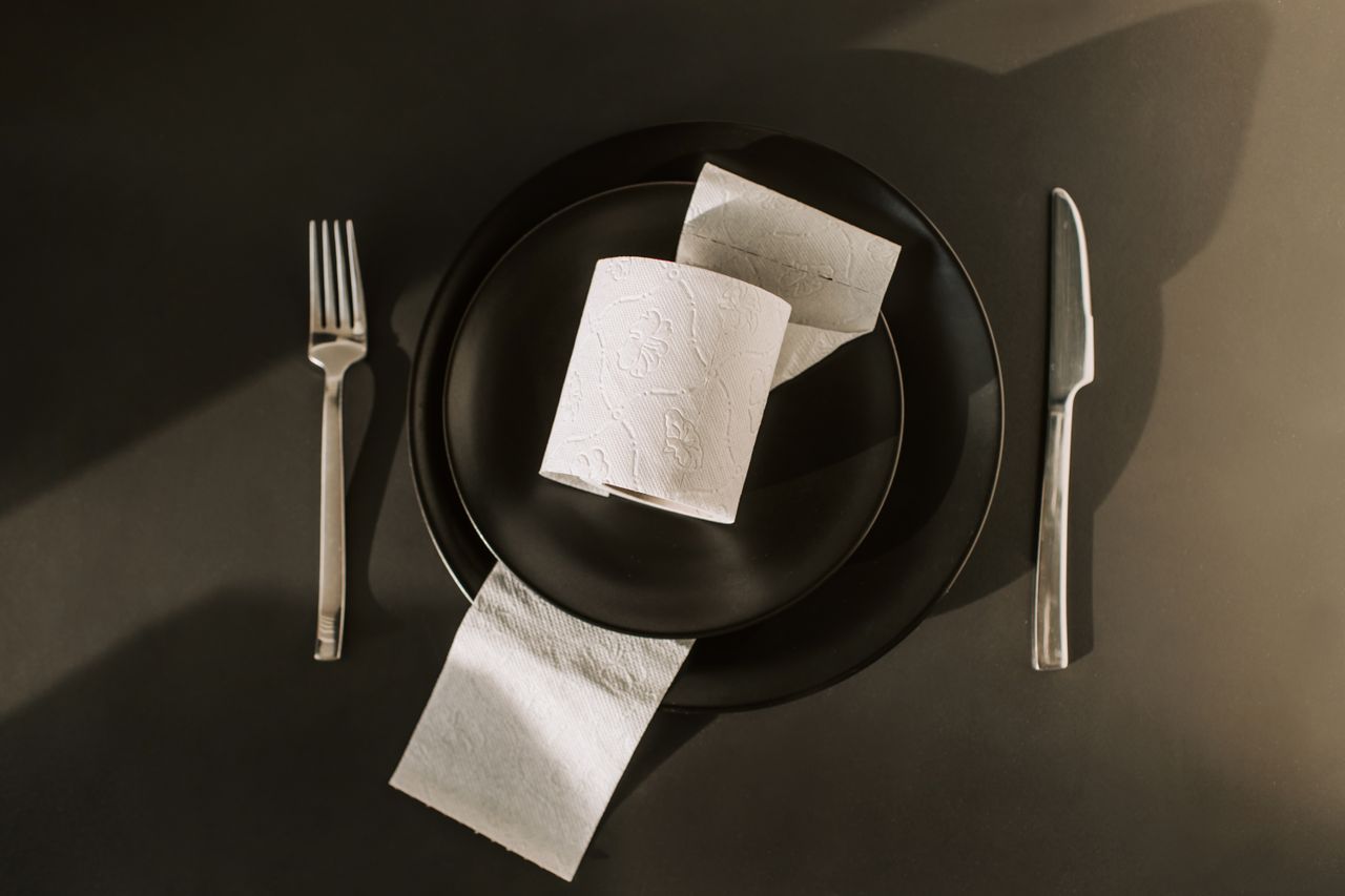 Conceptual still life with toilet paper roll on black plate, symbolizing hygiene and pandemic awareness.